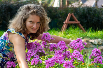 Obraz na płótnie Canvas Gardening - a girl caring for pink phlox in a flower bed