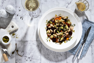 vegan salad of Soviet cuisine Vinegret with beets and white beans. white wine on a marble table