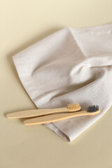 Two ecological wooden toothbrushes lying on white towel.
