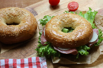 Seeded bagel filled with salad, onions, tomatoes and salami