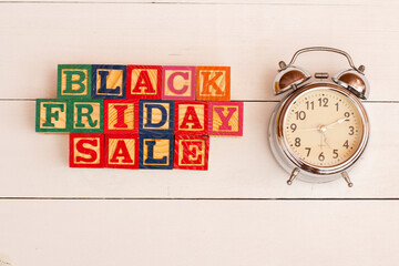 SPECTACULAR CONCEPT OF BLACK FRIDAY AND SALES WITH WOODEN CUBES AND WITH WOODEN SURFACE WITH OLD ALARM CLOCK.