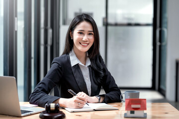 Beautiful Asian businesswoman lawyer sitting at the office holding a pen taking note working on a...