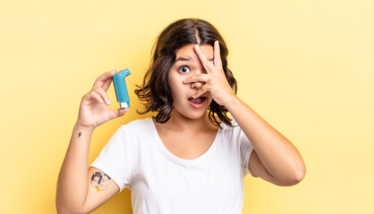 young hispanic woman looking shocked, scared or terrified, covering face with hand. asthma concept