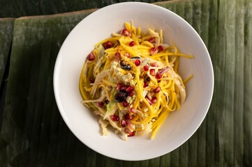 mango salad with berries and coleslaw in a white bowl on a banana leaf 