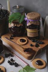 Black currant jam in glass jars and round cookies with blackcurrant jam for breakfast on white...