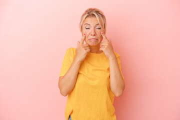 Young Russian woman isolated on pink background crying, unhappy with something, agony and confusion concept.