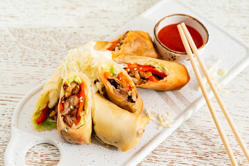  Traditional japanese appetizer, gourmet spring rolls made of fresh vegetables on a white paper background.