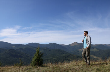 Naklejka na ściany i meble Man enjoying picturesque view of mountain landscape on sunny day