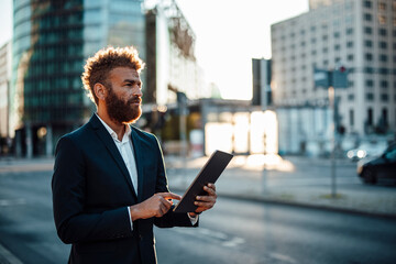 Mature male professional holding digital tablet while standing on street