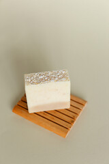 Haomemade white herbal soap with olive oil on wooden stand.
