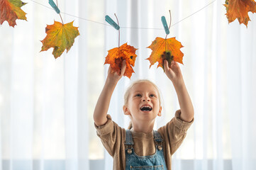 child making a garland of yellowed leaves