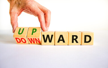 Upward or downward symbol. Businessman turns wooden cubes and changes the word 'downward' to 'upward'. Beautiful white table, white background. Business, upward or downward concept. Copy space.