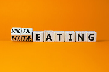 Mindful or intuitive eating symbol. Turned wooden cubes and changed words intuitive eating to mindful eating. Beautiful orange background, copy space. Medical and mindful or intuitive eating concept.