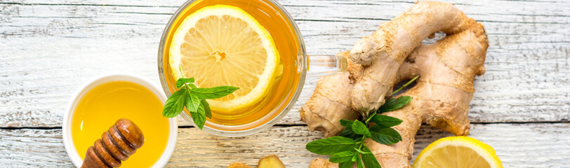 banner of Ginger tea with lemon mint and honey on a white wooden background. Hot healthy winter...