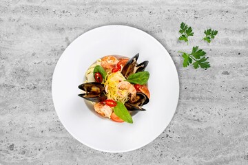 Mixed tasty seafood in plate on a gray stone background. Raw Shrimp, mussels and scallops