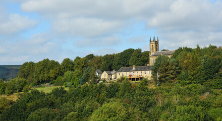 Fototapeta na wymiar Village of Tintwistle on a Derbyshire hillside church houses and trees.