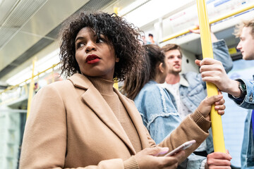 Busy tube, people commuting, black woman holding phone