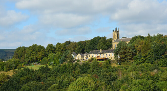 Village of Tintwistle  on a Derbyshire hillside church houses and trees.