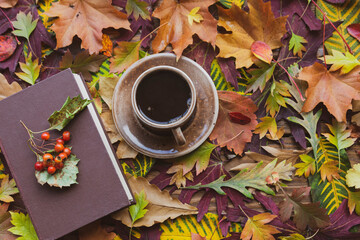 Autumn background. Autumn leaves: a cup of hot coffee and a book on a wooden table.