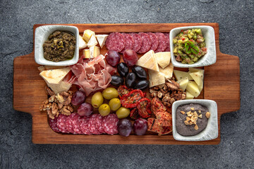Plateau snack for wine. Prosciutto, smoked sausage, olives, cheese, pates. Food for a large company. Ready menu for the restaurant. Neutral gray blue textured background