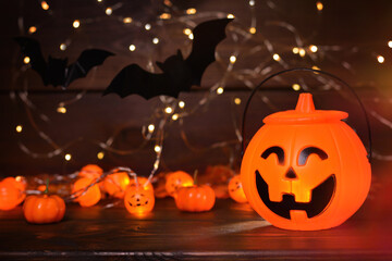 Glowing Halloween handbag in the form of a pumpkin, bats on wooden background with bokeh lights.Halloween trick or treat!Сopy space for text.Halloween background