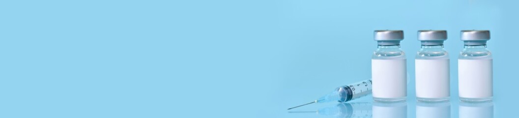 Three vials with a vaccine, a syringe on a blue background.The concept of medicine, healthcare and science.Coronavirus vaccine.Copy space for text..Banner