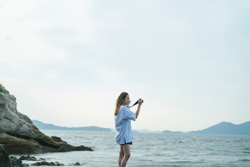 Fototapeta na wymiar 夕暮れの海で写真を撮るカメラ女子