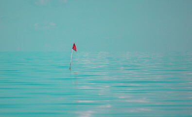 Red flag marking fishing net in the water