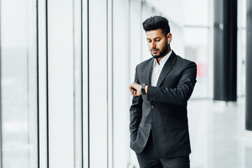 Portrait of a handsome successful Indian businessman standing in the middle of a modern building, busy Indian man, office worker