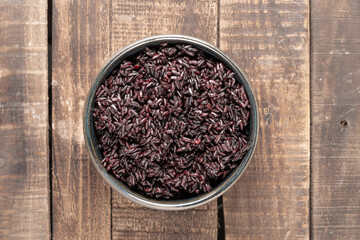 Healthy food black rice in a bowl on a wood table.