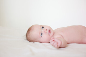 small child, baby lies on his stomach and smiles. On a white background. Newborn baby. three months old baby. A baby of European appearance. selective focus