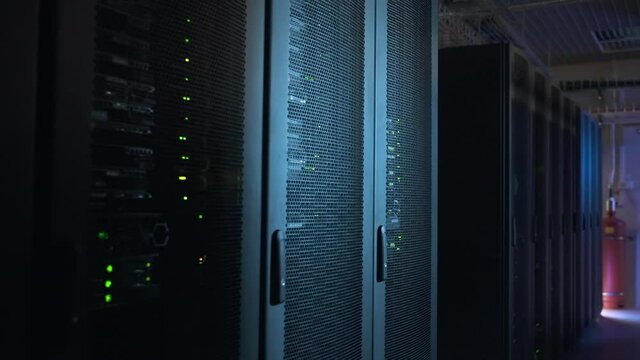 Moving shot of dark interior of big data center with working equipment and servers spbas. Black racks with hardware or software works and blinks in room without people. This is where high tech systems