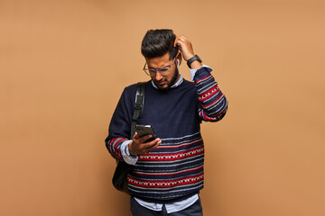 Bearded hindu student in glasses with backpack surfing his smart