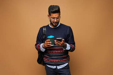 Handsome hindu man with coffe and backpack make call on his mobile phone