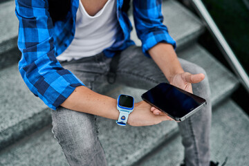 Close up blue kid smart watch and mobile phone in boy hand