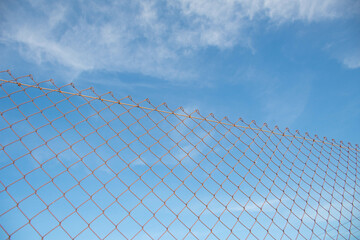 Wire fence protecting a private area and in the background a blue sky with few clouds