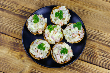 Traditional Russian festive salad Olivier in tartlets on wooden table