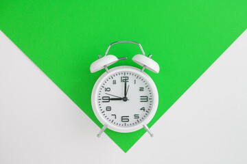 White alarm clock on the green and white background. Top view. Copy space. Location vertical.