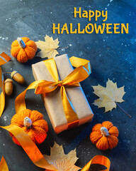 Happy Halloween conceptual composition. Gift box with orange ribbon, knitted pumpkins