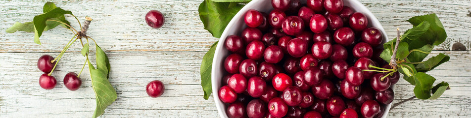 banner of Fresh sweet cherries white bowl with leaves in water drops on wooden background