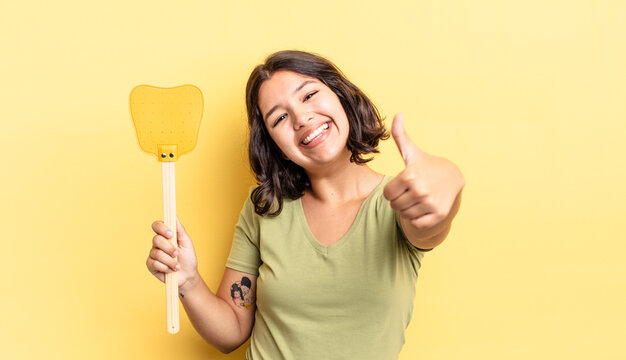 Young Hispanic Woman Feeling Proud,smiling Positively With Thumbs Up. Kill Flies Concept