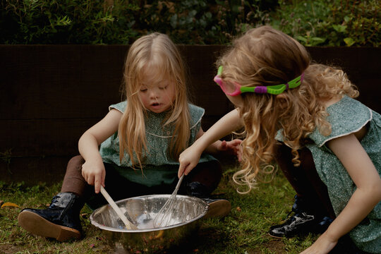 Twin girls with Down Syndrome playing with water and paint powder outdoors