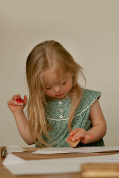 Little girl with Down Syndrome playing with stamps and red ink