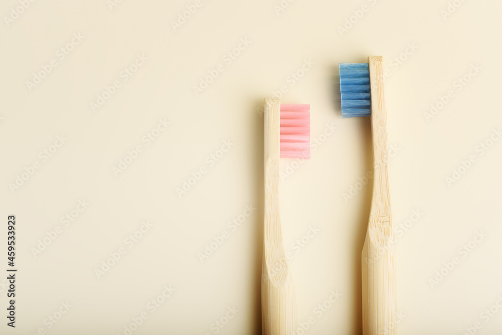 Wall mural Two eco friendly pink and blue natural bamboo toothbrushes on beige background. Health care, copy space. Zero waste concept.