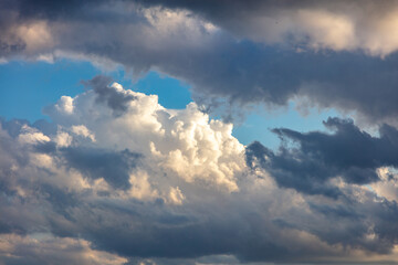 Fluffy cumulus clouds on blue sky background. Cloudscape white and grey color
