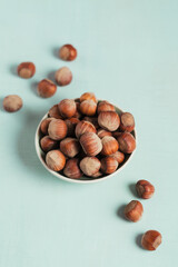 Pile of hazelnuts filbert in a bowl on a light blue background