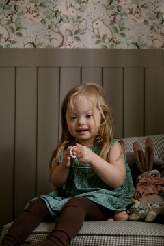 Portrait of little girl with Down Syndrome sitting on chair and smiling
