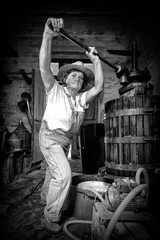Grape harvest: Old woman winemaker  working on a traditional winepress for the must pressing. Black and white picture