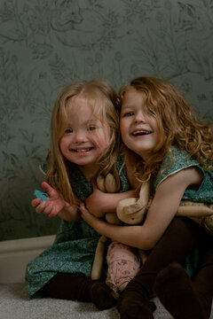 Twin girls with Down Syndrome hugging each other and smiling