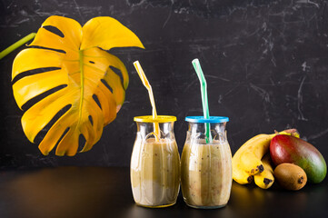 Two glasses of fruit cocktail. Two glasses with straws. Fruit and cocktail on a black background.